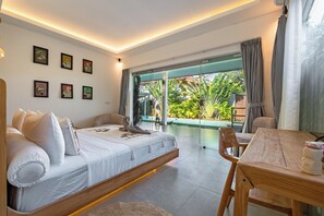 A modern bedroom with a sofa bed, a dining table, and a view of a garden through large glass doors. - Bingin Villas: Luxury, Concierge & Security (Badung)