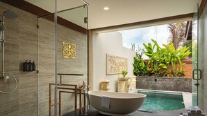 Ein modernes Badezimmer mit einer Duschkabine aus Glas, einer freistehenden Badewanne und einem kleinen Pool.
