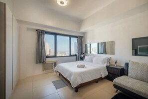 Ein modernes Hotelzimmer mit einem großen Bett, einem Schreibtisch, einem Stuhl und Blick auf die Stadt.