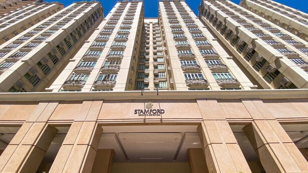 Een hoog gebouw met een opvallend 'STAMFORD' sign, met een symmetrische gevel, meerdere balkons en een centrale ingang.