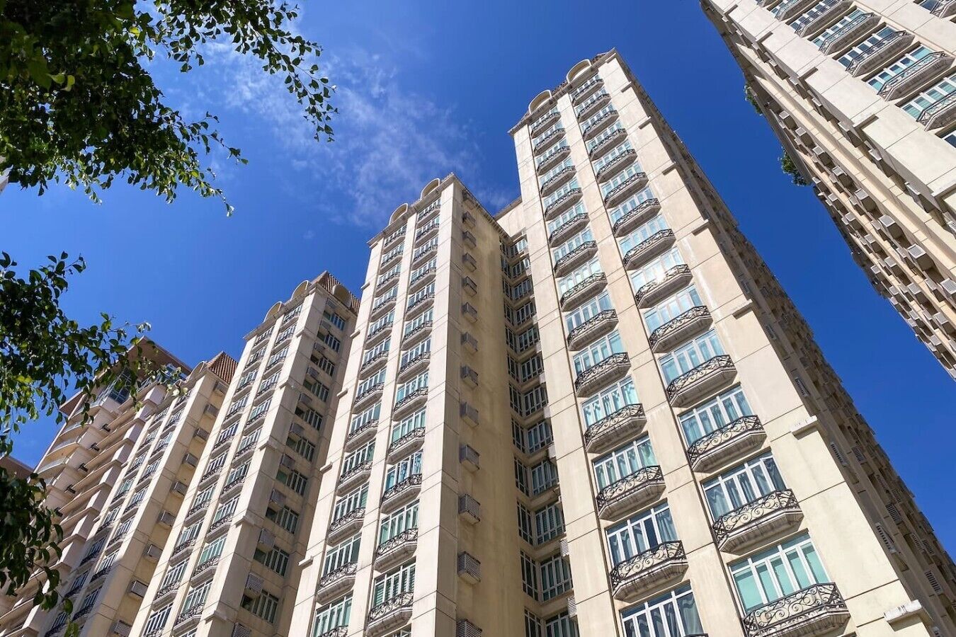 Een hoog appartementencomplex met meerdere balkons, grote ramen en een heldere lucht.