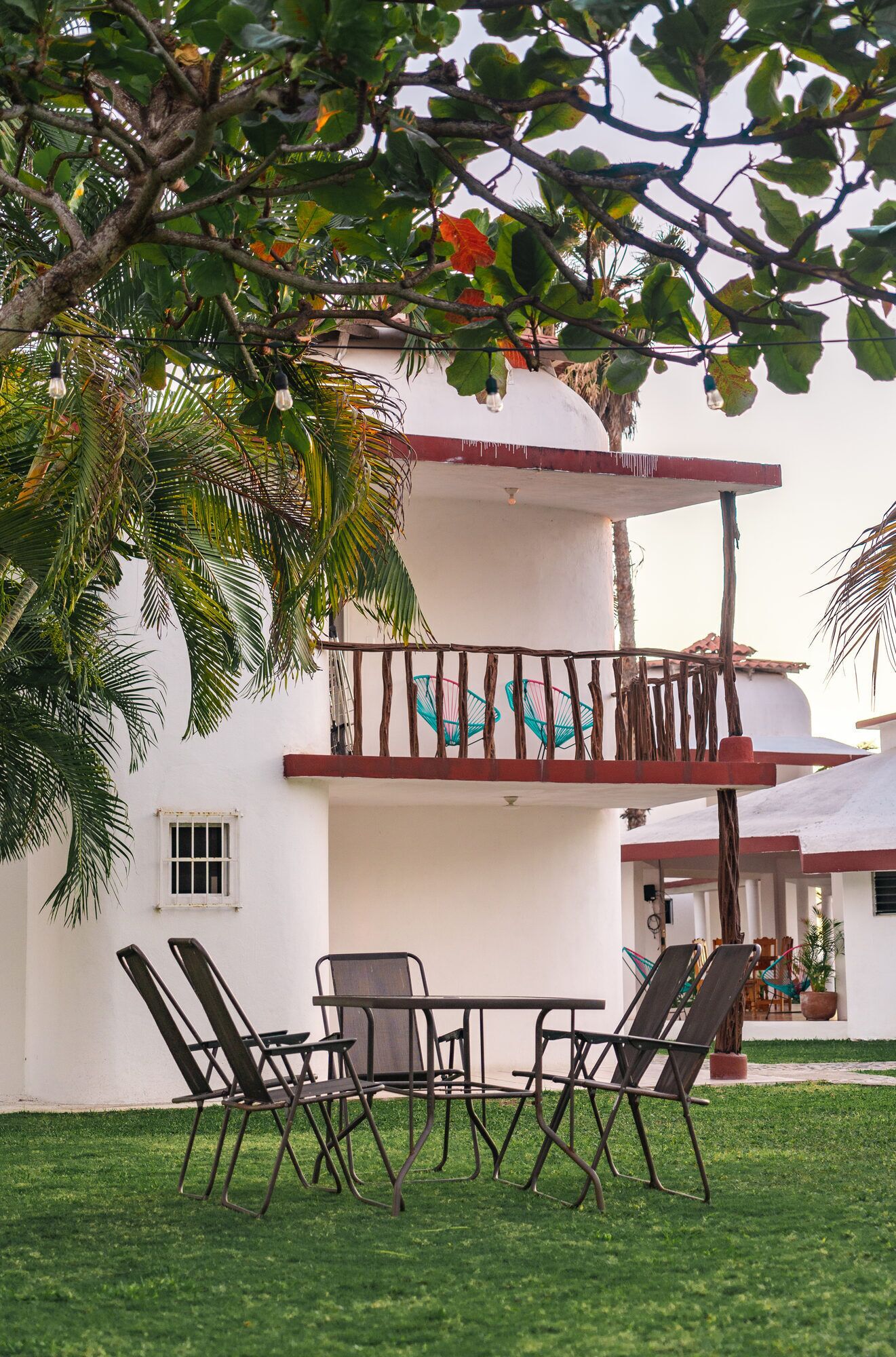 A two-story building with a balcony, outdoor seating, and a lawn.