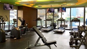 A gym with treadmills, elliptical machines, and weight benches. - StayHere Fast WiFi 5 Star View in Makati (Makati)