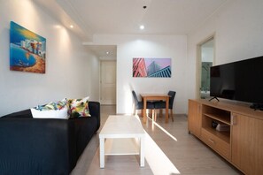 Ein modernes Wohnzimmer mit einer Couch, einem Couchtisch, einem Fernseher und Kunstwerken an den Wänden.