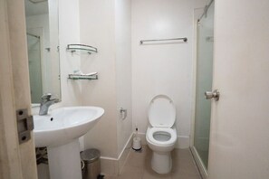 Ein kleines Badezimmer mit einem weißen Waschbecken, einer Toilette und einer Duschkabine aus Glas.