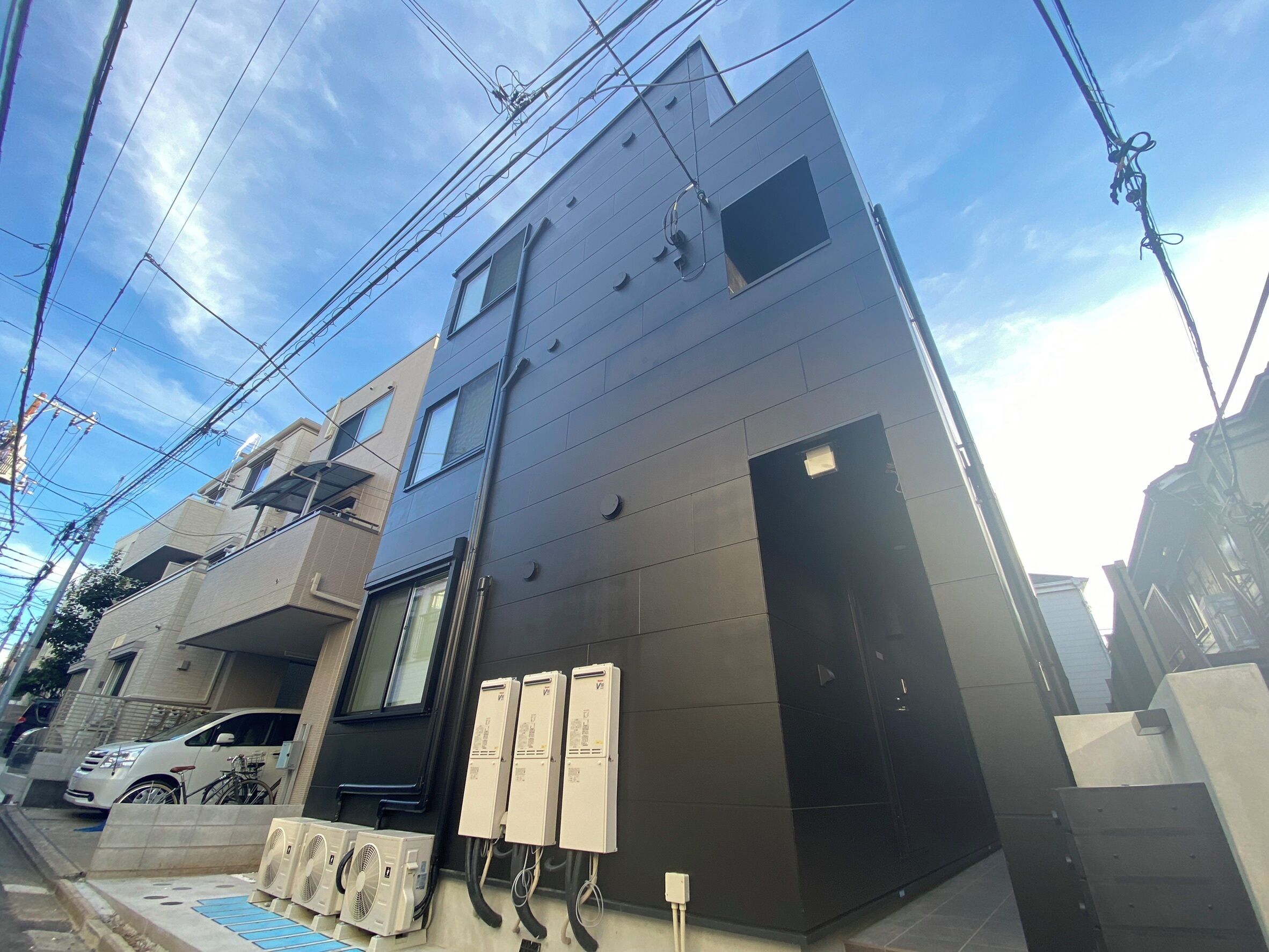 A modern building with multiple floors, visible electrical wiring, and a bicycle parked outside.