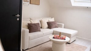 Een moderne woonkamer met een witte bank, een ronde salontafel en een zwarte deur.