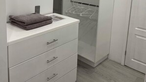 Ein begehbarer Kleiderschrank mit weißem Schminktisch, einer Kleiderstange und einer Tür.