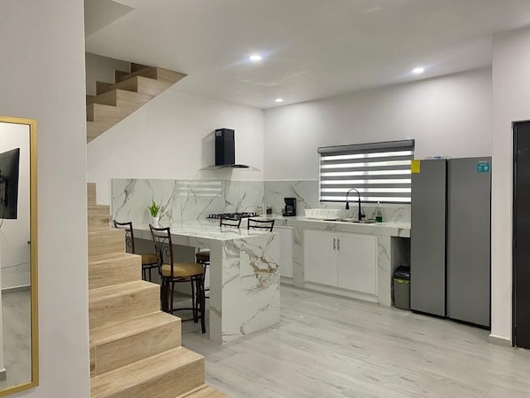 A modern kitchen with marble countertops, a built-in stove, and a refrigerator.
