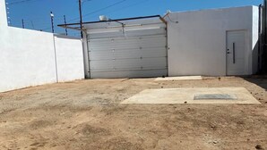 Ein Gebäude mit geschlossenem Garagentor, einer Betonauffahrt und einer weißen Wand.