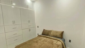 Ein Schlafzimmer mit Bett, Kleiderschrank und Deckenleuchte.