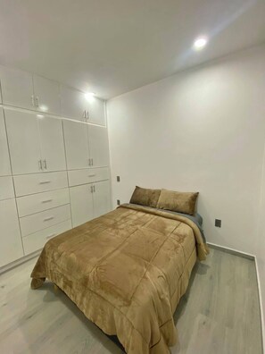 A bedroom with a bed, a wardrobe, and a ceiling light.