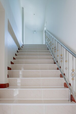 A staircase with a metal railing and beige tiles.