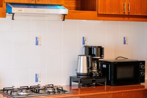 A kitchen with a gas stove, a coffee maker, and a microwave.