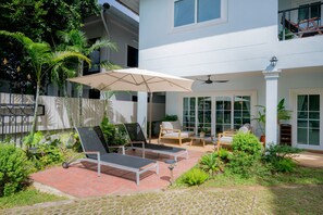 A patio area with two lounge chairs, a table, and an umbrella.