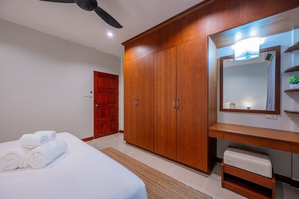 A bedroom with a bed, wooden wardrobe, and a large mirror.