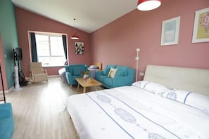 A hotel room with a bed, a sofa, a chair, a small table, and a TV.