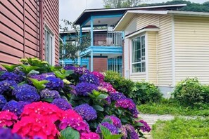 A house with a balcony, surrounded by lush greenery and vibrant flowers.