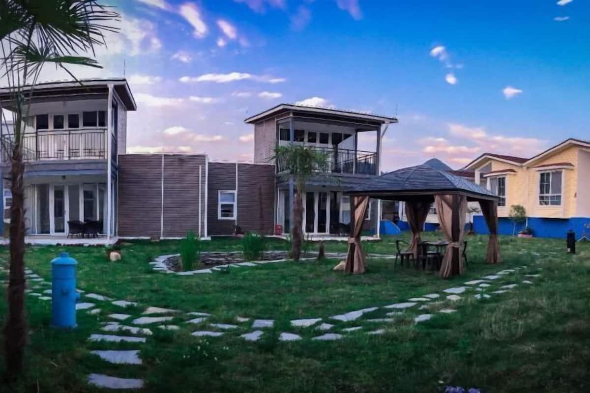 A residential area with a gazebo, a covered outdoor seating area, and a pathway leading to a building with a balcony.