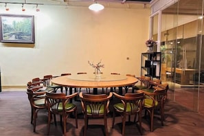 A round table with chairs, a vase with flowers, and a painting on the wall.