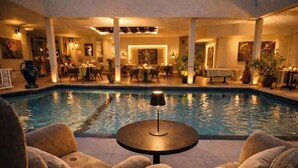 Un área de piscina con sillones reclinables, una mesa y un comedor con sillas y mesas.