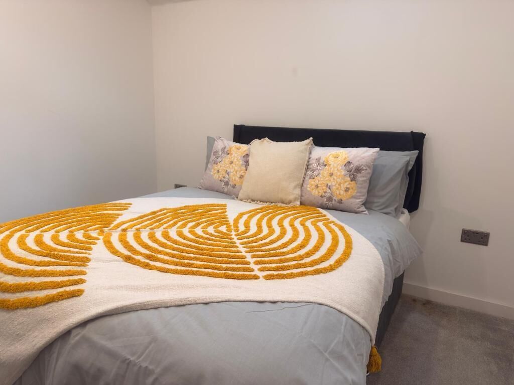 A bed with a patterned blanket, a dark headboard, and two pillows with floral designs.