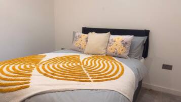 A bed with a patterned blanket, a dark headboard, and two pillows with floral designs.