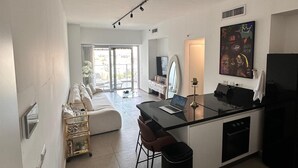 Ett modernt kök med en central köksö, en matplats med soffa och ett stort fönster som släpper in naturligt ljus.