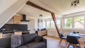 A modern loft apartment with a kitchen, dining area, and a large window.