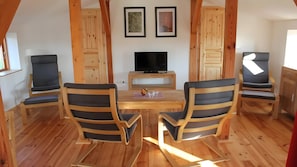Ein Essbereich mit Holztisch, einem Fernseher, vier Stühlen und zwei gerahmten Bildern an der Wand.
