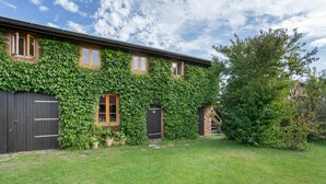 A building with ivy-covered walls, a brick entrance, and a grassy yard. - Apartment "Galerie" – Cozy Retreat Near Water and Forest (Kröslin)