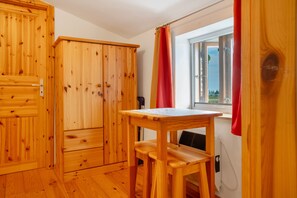 Een kamer met houten vloer, een raam, een tafel en een stoel.