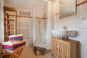 Ein Badezimmer mit Dusche, Waschbecken, einem Holzkabinent und einem Handtuchhalter mit Handtüchern.