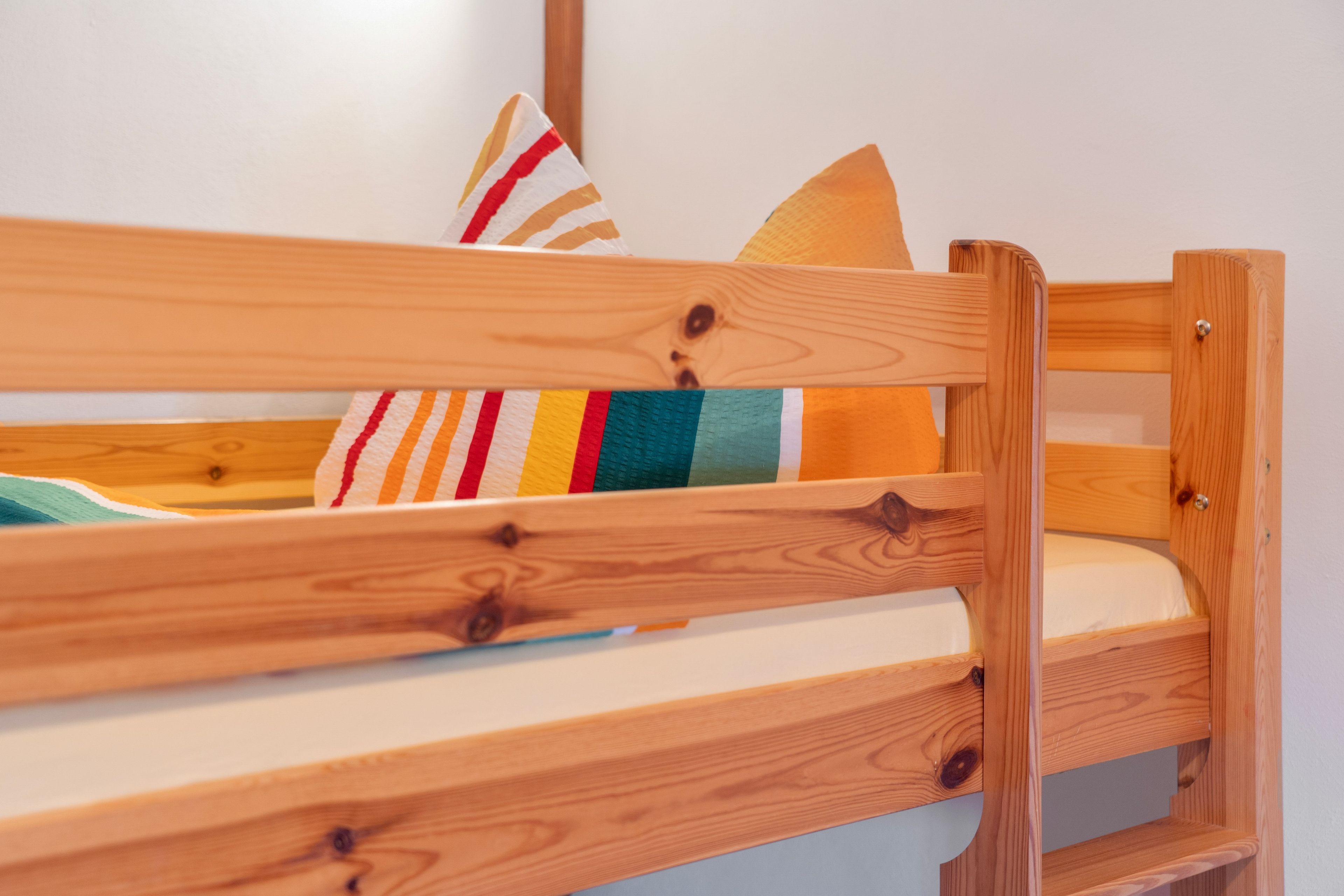 A wooden bunk bed with a mattress and pillows.