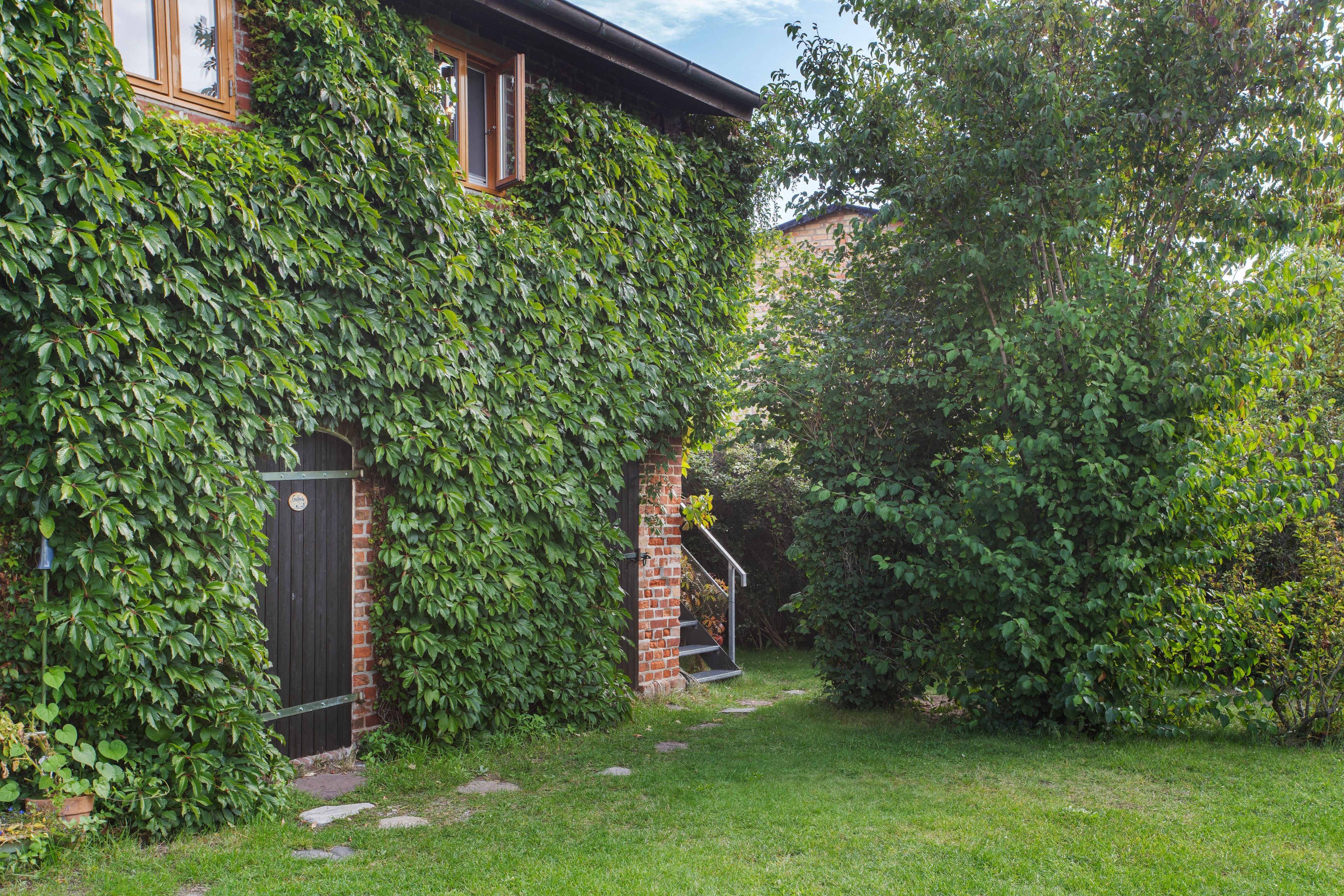 Una casa de ladrillo con porche cubierto y jardín.