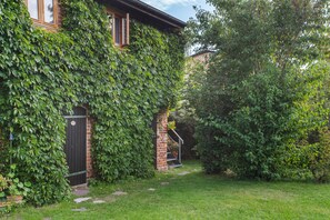 Een bakstenen huis met een overdekte veranda en een tuin.