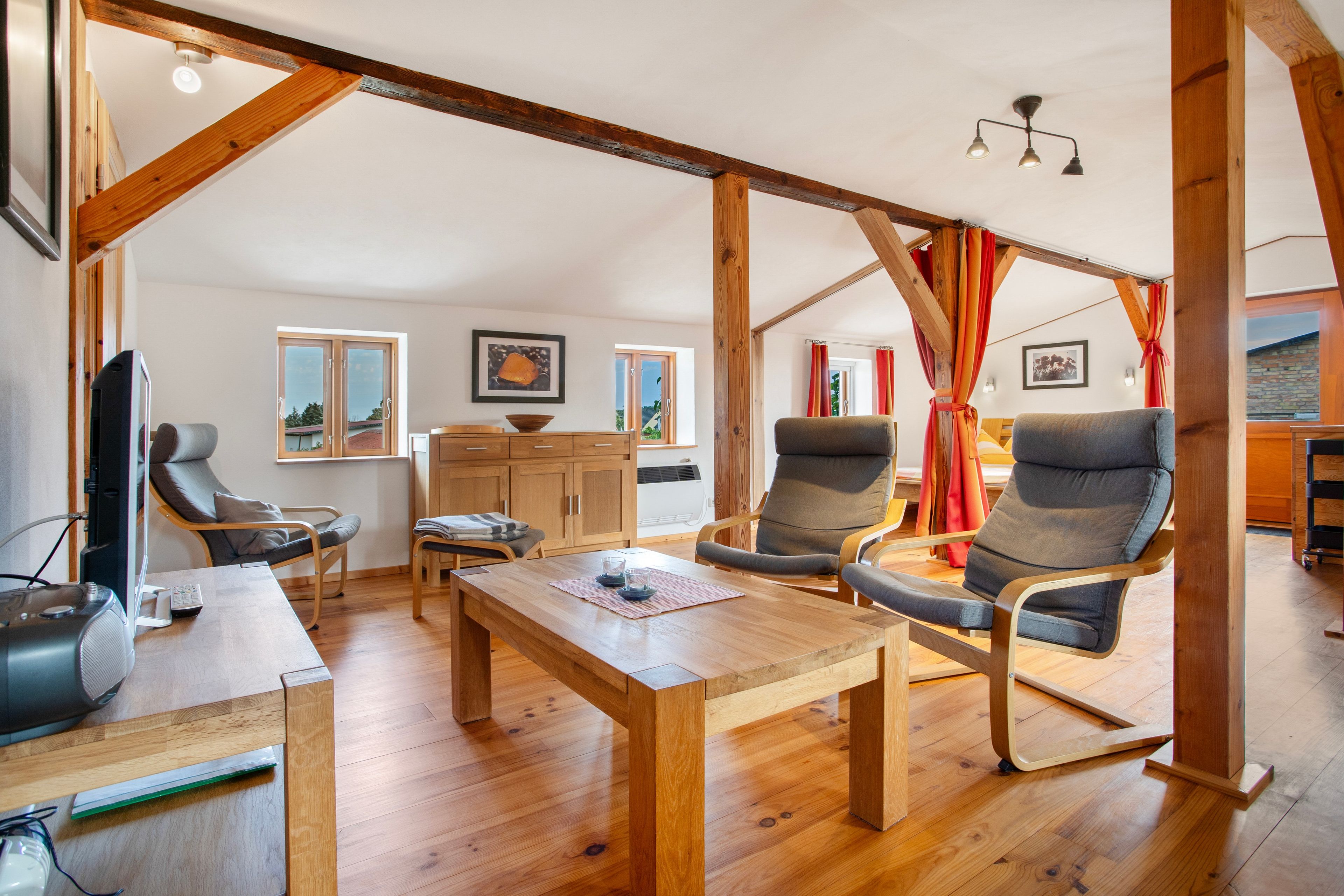 A spacious living area with a wooden table, two armchairs, a sofa, and a television.