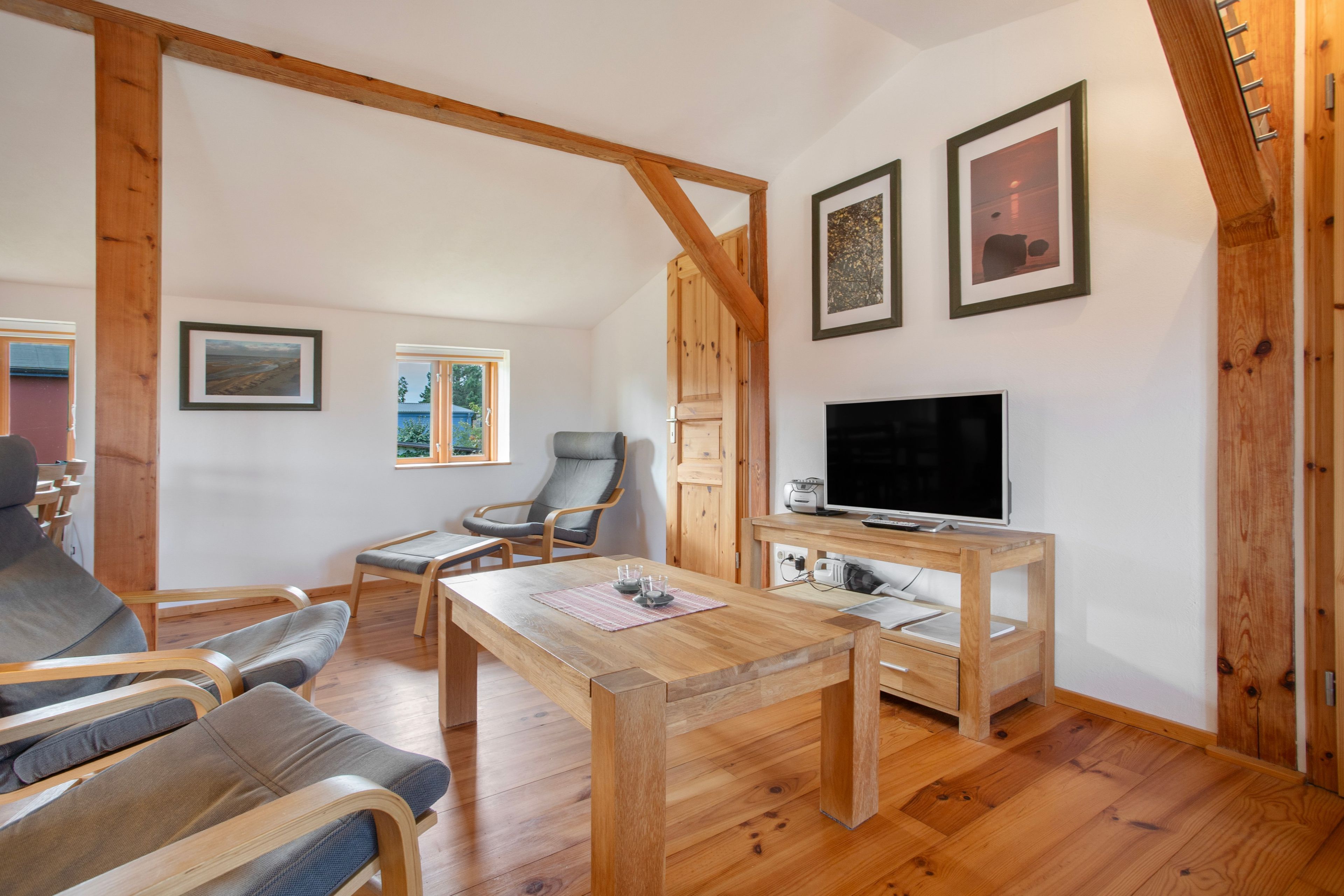 Un salon chaleureux, doté de meubles en bois, d’un téléviseur à écran plat et d’œuvres d’art encadrées accrochées au mur.