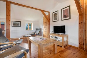 Una sala de estar acogedora con muebles de madera, un televisor de pantalla plana y cuadros en la pared.