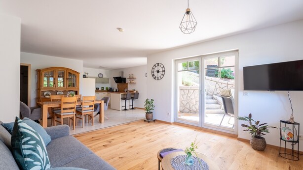 Een moderne woonkamer met een bank, een eettafel en een keuken op de achtergrond.