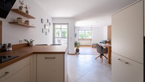 Een moderne keuken met houten planken, een eethoek met een tafel en stoelen, en uitzicht op de omgeving.