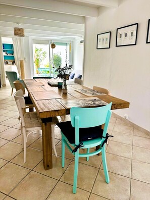 A dining area with a wooden table, teal chairs, and a vase with dried flowers. - Ker Marin'o - 5 personnes (Les Sables-d´Olonne)