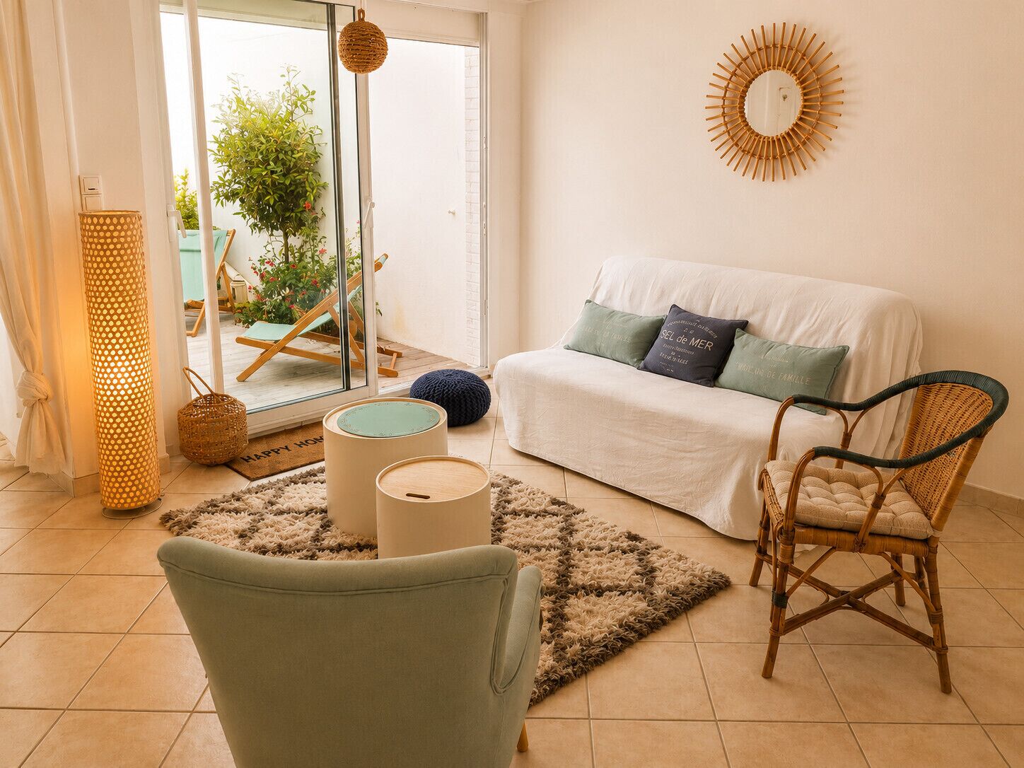 A living room with a sofa, chair, lamp, and a view through a glass door.