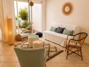 Ein Wohnzimmer mit einer Couch, einem Sessel, einer Lampe und Blick durch eine Glastür.