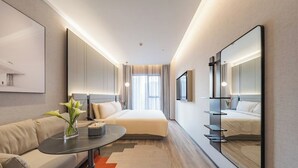 A modern hotel room with a bed, a sofa, a coffee table, a mirror, and a large window. - Atour S Hotel - Shanghai World Expo Lujiaizui Riverside Center  (Shanghai)