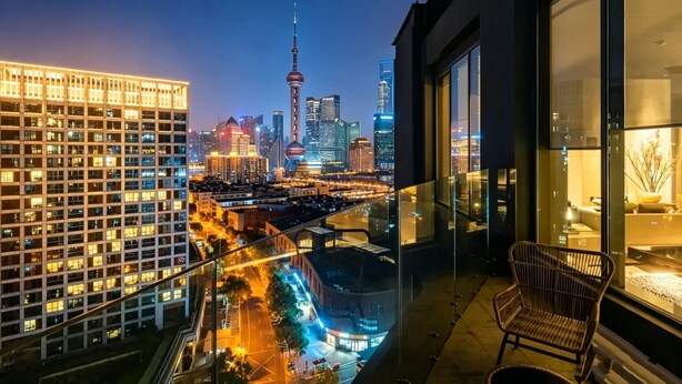 A cityscape with a prominent tower, a modern building with illuminated windows, and a balcony with a chair. - Atour S Hotel - Shanghai World Expo Lujiaizui Riverside Center  (Shanghai)