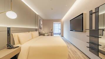 Una habitación de hotel moderna con una cama grande, mesita de noche y un televisor montado en la pared.