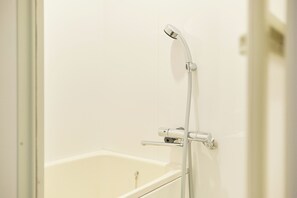 Ein Badezimmer mit einer Badewanne, einer Duschbrause und einem Wasserhahn.