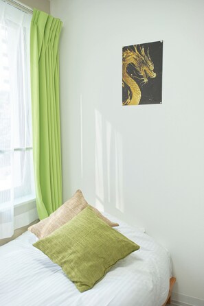 Ein Schlafzimmer mit einem Bett, grünen Vorhängen, einem Wandbild eines Drachen und einem Fenster mit transparenten Vorhängen.
