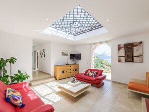 A spacious living room with a high ceiling, a television, a red sofa, a wooden cabinet, and a view of the outdoors. - Kanelata by Interhome (Canari)